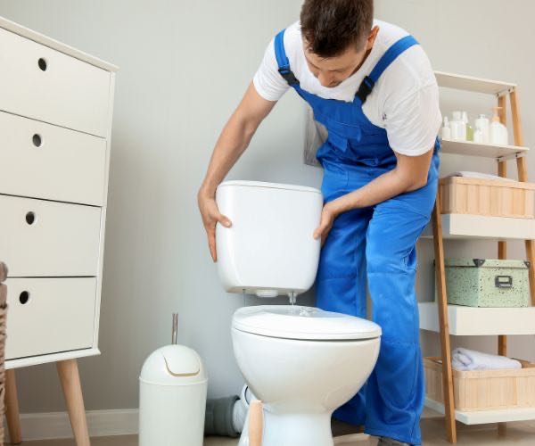 Installateur bei der Montage einer Toilette und des Spülkastens